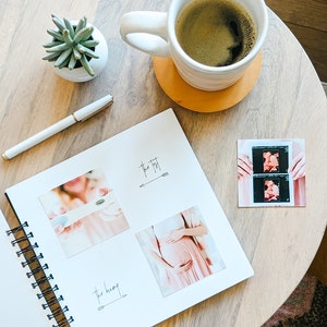 Puede incluir: Un diario de embarazo blanco en espiral con un bol&iacute;grafo negro y una taza de caf&eacute; sobre una mesa de madera. El diario tiene una secci&oacute;n para "The First" e incluye fotos de una ecograf&iacute;a y una mujer embarazada.