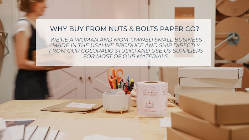 K&ouml;nnte beinhalten: Ein wei&szlig;er Schreibtisch-Organizer mit orangefarbener Schere, Stiften und Markern, neben einer Rolle wei&szlig;er Etiketten und gestapelten Versandkartons. Der Text auf dem Bild lautet: WHY BUY FROM NUTS & BOLTS PAPER CO? WE'RE A WOMAN AND MOM-OWNED SMALL BUSINESS.