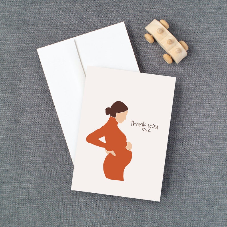 May include: A white card with a simple illustration of a pregnant woman in an orange dress. The text "Thank you" is written in cursive on the card.
