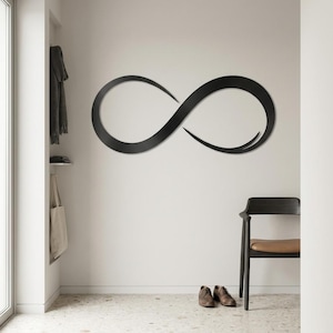 Può includere: Un complemento d'arredo da parete in metallo nero opaco a forma di simbolo dell'infinito stilizzato. Il design presenta una linea continua e fluida che si intreccia per formare il classico otto, con estremità affusolate che creano movimento.