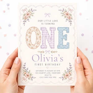 May include: A rectangular birthday invitation card featuring a scalloped border with floral accents. The text reads: Our little love is turning ONE, Olivia's first birthday, Saturday 16 August at 2pm, 123 Country Lane, Yourtown, RSVP to Lilly 0400 000 000.
