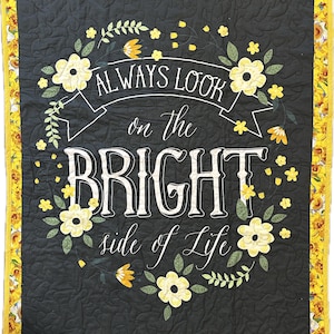 May include: A quilted wall hanging with the text "ALWAYS LOOK on the BRIGHT side of Life" in white script. The black background is decorated with yellow flowers and green leaves. The border is yellow with a floral pattern.