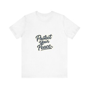 May include: A white short-sleeved t-shirt featuring the text "Protect Your Peace." printed in a dark navy blue cursive script font across the center of the chest. The garment has a crew neckline and a standard fit with short sleeves.
