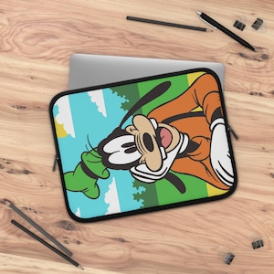Op de afbeelding: Een rechthoekige laptophoes met een grafische print van het stripfiguur Goofy. Het personage is afgebeeld met een beige gezicht, zwarte oren en een oranje shirt tegen een achtergrond van een blauwe lucht en een groen landschap met witte wolken.