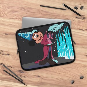 Op de afbeelding: Een zwarte laptophoes met een afbeelding van een tekenfilmmuis die een blauwe tovenaarshoed met maan- en sterpatroon en een lange magentakleurige mantel draagt, wijzend naar een verticale stroom van lichtblauw magisch licht.