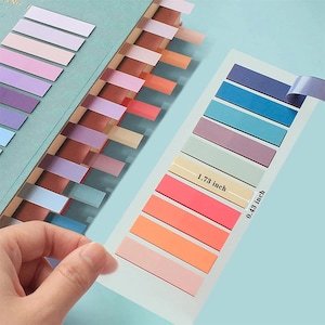 May include: A set of rectangular adhesive page markers in various colors, including shades of blue, purple, pink, and orange. The markers are arranged on a clear backing sheet, with one strip measuring 1.73 inches in length and 0.43 inches in width.
