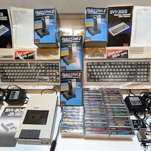 以下が含まれることがあります： ベージュ色のSVI-328パーソナルコンピューター2台、箱入りQuickShot Iジョイスティックコントローラー2個、SVI-904データカセットレコーダー、複数のソフトウェアカセットテープ、電源アダプター、コンピューターおよびレコーダー用のユーザーマニュアル。
