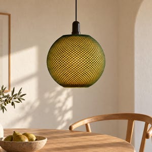 May include: A spherical pendant light fixture featuring a textured, cross-hatched green glass shade. The lamp is suspended by a thin black cord attached to a dark brown cylindrical mount at the top, emitting a warm, soft internal glow.
