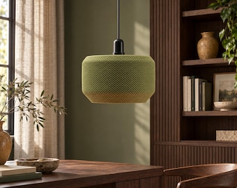 May include: A cylindrical pendant light fitting featuring a textured, lime green mesh shade with a subtle gradient effect. The shade is suspended from a thin black cord attached to a black socket, creating a focused downward light source.