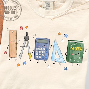 May include: A cream-coloured t-shirt featuring a graphic of five anthropomorphic school supplies: a wooden ruler, a metal compass, a blue calculator, a light blue triangle ruler, and a green book labelled MATH with E=mc2 and pi symbols.