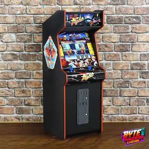 May include: A miniature black arcade cabinet featuring Final Fight branding, a screen displaying gameplay, a control panel with two blue joysticks, and a coin slot panel. The cabinet has orange trim and colorful character graphics on the side.
