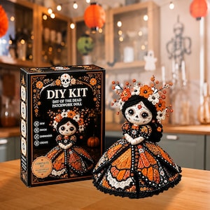 May include: A DIY kit box labeled Day of the Dead Patchwork Doll next to a finished doll featuring a black and orange butterfly-patterned dress, a skull-painted face, and a floral headpiece with orange and white flowers and small brown branches.