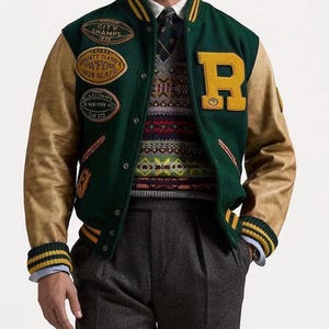 Puede incluir: Una chaqueta universitaria verde con mangas de color tostado, que presenta un gran parche amarillo con la letra R en el pecho, varios parches deportivos bordados y puños acanalados a rayas. Debajo lleva un suéter de punto estampado y camisa blanca.