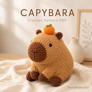 May include: A crochet capybara plush toy with a light brown body, dark brown snout and feet, and a small orange fruit on its head. The text CAPYBARA Crochet Pattern PDF and ThreadByRoseArt are visible in the image.