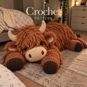 Può includere: Un grande giocattolo fatto a mano all'uncinetto che raffigura una mucca delle Highlands con una lunga pelliccia di filato color ruggine, corna color crema e zoccoli marrone scuro. Il testo "Crochet PATTERN" e "ThreadByRoseart" sono visibili.