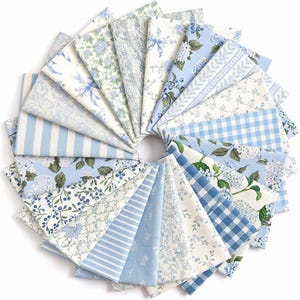 May include: A collection of fabric squares arranged in a circular fan pattern, featuring various light blue and white prints including gingham checks, vertical stripes, floral patterns, botanical vines, and small berry motifs on cotton textiles.