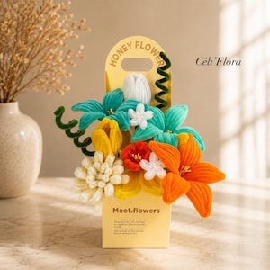 Peut inclure: Un bouquet de fleurs en cure-pipes colorés dans une boîte en carton jaune marquée Honey Flower et Meet.flowers avec le texte Céli'Flora. L'arrangement comprend des fleurs bleu sarcelle, jaunes, orange, rouges et blanches avec des tiges en spirale.