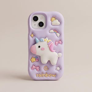 May include: A light purple phone case featuring a raised white unicorn with a pink mane and horn. The case is decorated with embossed icons including a sun, clouds, a rainbow, stars, and bows. The word rainbow is printed in yellow at the bottom.
