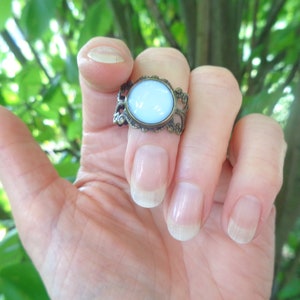 Op de afbeelding: Een ring met een lichtblauwe ovale steen in een bronzen filigraan setting.