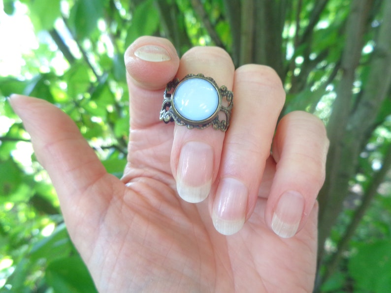 Op de afbeelding: Een ring met een lichtblauwe ovale steen in een bronzen filigraan setting.