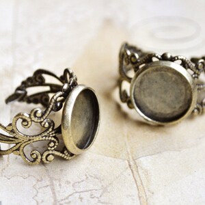 May include: Two antique gold-toned rings with a round, open bezel setting. The rings are made of filigree metal with a delicate, ornate design.