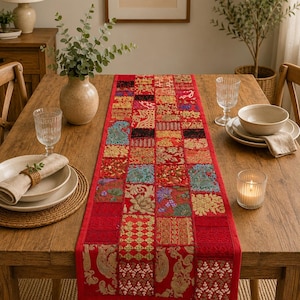 May include: A rectangular table runner featuring a patchwork design of various red fabric squares. Each square displays distinct embroidered patterns, floral motifs, and metallic gold thread accents, creating a vibrant, multi-textured surface.