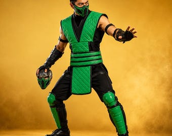 May include: A green and black ninja costume featuring a quilted vest, matching green face mask, black arm guards, and green shin guards. The outfit includes a black base layer, a wide green waist sash, and a separate green and silver face mask.