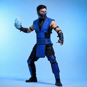 May include: A blue and black quilted vest and trousers costume featuring a matching blue and black face mask, black arm guards, and blue knee and shin guards. The costume includes a glowing light blue ice-like head sculpture held in one hand.