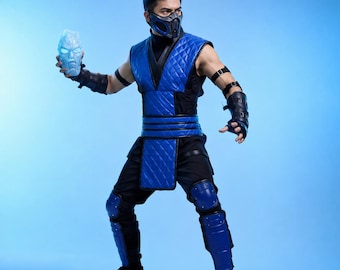 May include: A blue and black quilted vest and pants costume featuring a matching blue and black face mask, black arm guards, and blue knee and shin guards. The costume includes a glowing light blue ice-like head sculpture held in one hand.