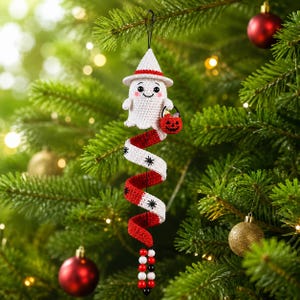 May include: A crocheted ghost ornament wearing a white pointed hat, holding a small red jack-o'-lantern bucket. Below the ghost is a red and white spiral tail decorated with black star patterns, ending with a string of red, white, and black beads.