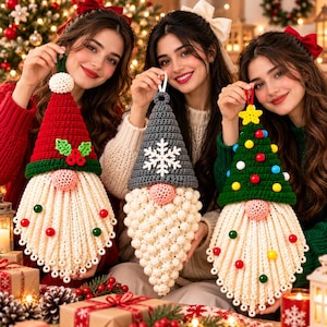 May include: Three handmade crochet gnome ornaments featuring festive designs. The left gnome has a red hat with holly, the centre has a grey hat with a white snowflake, and the right has a green hat with a yellow star and colourful pom-pom ornaments.