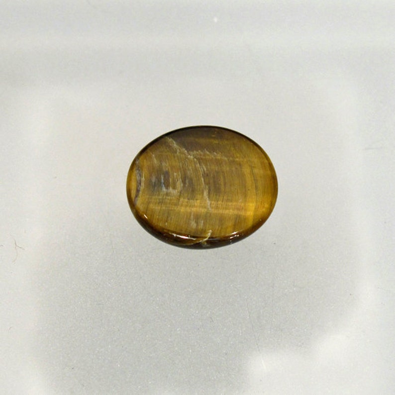 May include: A smooth, oval-shaped tiger's eye gemstone with a golden brown color and a subtle chatoyancy effect.