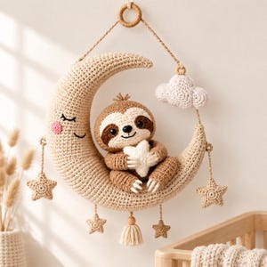 Peut inclure: Une suspension murale en forme de croissant de lune crocheté beige avec un paresseux marron et beige tenant une étoile blanche. La lune a un visage brodé aux joues roses, un nuage blanc crocheté et cinq petites étoiles beiges suspendues.