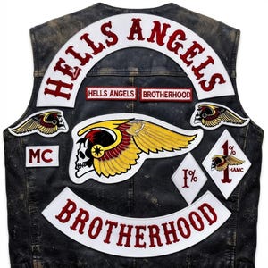 Puede incluir: Un chaleco de cuero negro con múltiples parches bordados. La parte posterior muestra un gran parche arqueado de HELLS ANGELS, un emblema central de calavera alada y un parche inferior de BROTHERHOOD. Incluye parches adicionales de MC, 1% y HAMC.