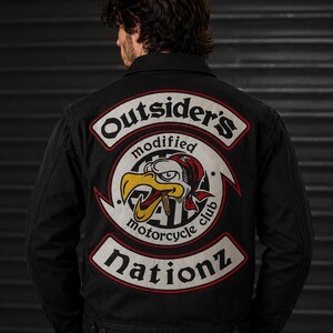 May include: A black denim jacket featuring a large embroidered back patch. The patch displays a central eagle wearing a red bandana and smoking a cigar, surrounded by the text Outsider's modified motorcycle club and the word Nationz below.