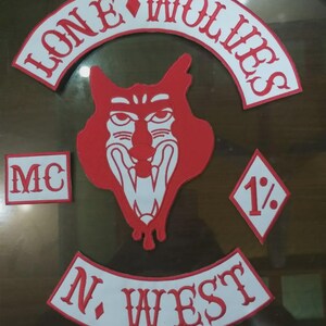 May include: A set of four embroidered patches featuring a red and white color scheme. The top arc reads LONE WOLVES, the center shows a stylized wolf head, the left rectangle reads MC, the right diamond reads 1%, and the bottom arc reads N. WEST.