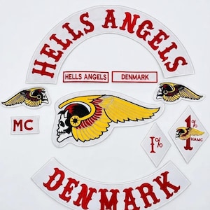 Puede incluir: Una colección de parches bordados con el texto HELLS ANGELS y DENMARK en rojo sobre fondo blanco. Incluye un emblema grande de calavera alada, dos parches más pequeños de calavera alada, dos parches en forma de diamante 1% y un parche MC.