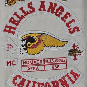 May include: A collection of embroidered patches featuring a large white arch with red text reading HELLS ANGELS, a central winged skull emblem, two diamond-shaped patches with 1% symbols, and rectangular patches labelled NOMADS, AFFA, and 666.