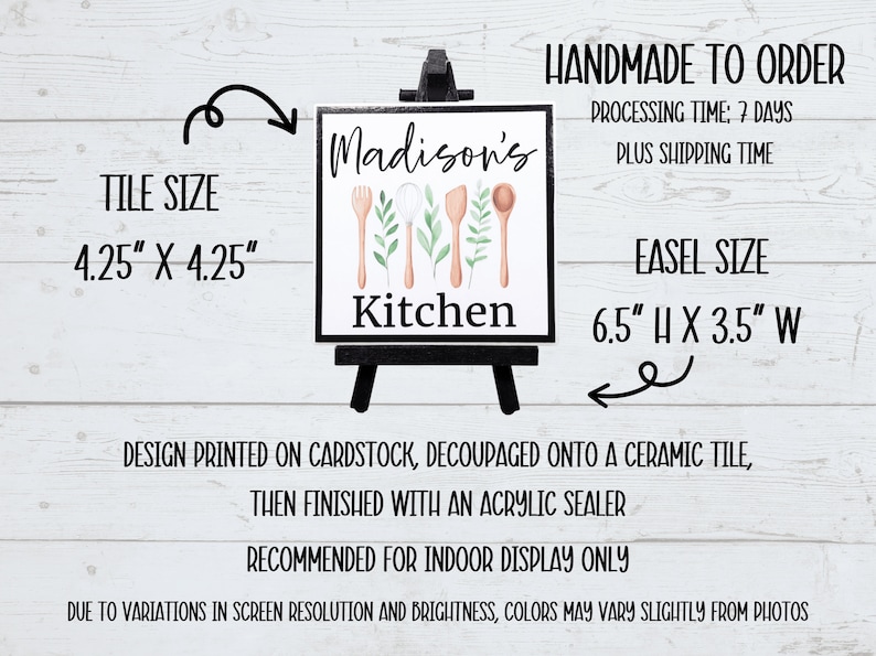K&ouml;nnte beinhalten: Eine wei&szlig;e Keramikfliese mit einem schwarzen Staffelei-St&auml;nder. Die Fliese zeigt ein Aquarell-Design mit K&uuml;chenutensilien und Gr&uuml;npflanzen. Der Text "Madison's Kitchen" ist auf die Fliese gedruckt.