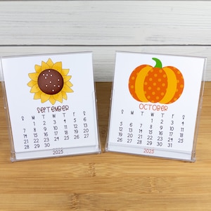 May include: Two desktop calendars with a sunflower and a pumpkin design. The September calendar features a yellow sunflower with a brown center and the October calendar features an orange pumpkin with brown stem and orange polka dots. Both calendars are for the year 2025.