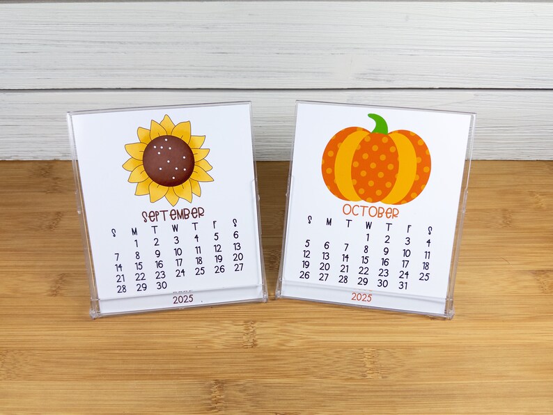 May include: Two desktop calendars with a sunflower and a pumpkin design. The September calendar features a yellow sunflower with a brown center and the October calendar features an orange pumpkin with brown stem and orange polka dots. Both calendars are for the year 2025.