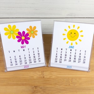 May include: Two small desktop calendars with a floral design for May and a sun design for June. The calendars are both for the year 2025.
