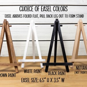 May include: Four wooden easels in different colors: brown, white, black, and natural. The easels are 6.5 inches tall and 3.5 inches wide. The text "Choice of Easel Colors" and "Easel arrives folded flat, pull back leg out to form stand" is at the top of the image.