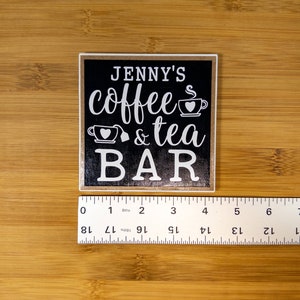 May include: Black wooden sign with white text that reads "JENNY'S coffee & tea BAR" with a coffee cup and teacup graphic.