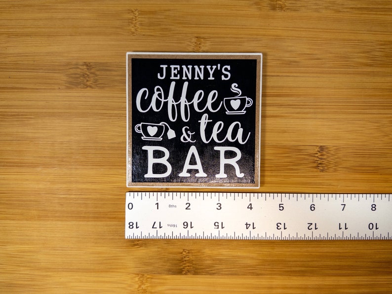 May include: Black wooden sign with white text that reads "JENNY'S coffee & tea BAR" with a coffee cup and teacup graphic.