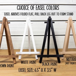 May include: Four wooden easels in different colors: brown, white, black, and natural. The easels are 6.5 inches tall and 3.5 inches wide. The text "Choice of Easel Colors" and "Easel arrives folded flat, pull back leg out to form stand" is at the top of the image.