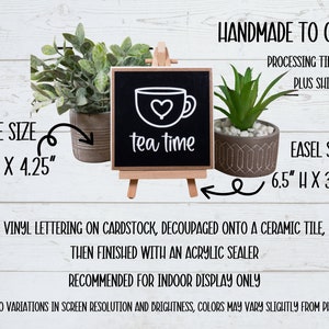 May include: A black chalkboard sign with a white teacup and the text "tea time" on a wooden easel. The sign is 4.25 inches by 4.25 inches and the easel is 6.5 inches high by 3.5 inches wide.