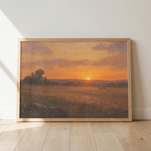 Könnte beinhalten: Ein rechteckiges Landschaftsgemälde in einem hellen Holzrahmen, das einen Sonnenuntergang über einem Feld zeigt. Der Himmel ist mit orangefarbenen, gelben und violetten Wolken über einer dunklen Horizontlinie gefüllt. Der Vordergrund zeigt eine Wiese.