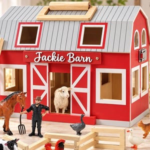 Peut inclure: Une grange jouet en bois rouge et blanc marquée Jackie Barn avec une poignée sur le dessus, une échelle et diverses figurines d'animaux en plastique dont un cheval, une vache, un âne, un mouton, un cochon, un coq, une oie, un chat, un chien, un fermier et un tracteur vert avec remorque.