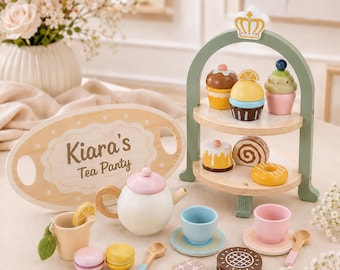 May include: A wooden toy tea set featuring a white teapot with a pink lid, a two-tiered serving stand with assorted play pastries, cups, saucers, spoons, and an oval wooden tray with the text Kiara's Tea Party printed in a dark brown script font.